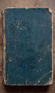 Antique Worn Prussian Blue Notebook Cover with Distressed Texture and Torn Edges on Wood Background