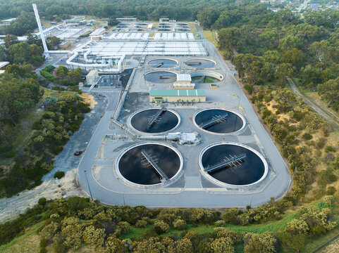 Aerial view of a water treatment plant with circular sedimentation tanks, filtration basins, and surrounding eucalyptus forest in Perth, Western Australia, Australia.