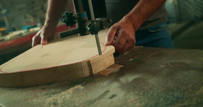 Artisan cutting natural wood with an industrial woodworking machine in a professional workshop, capturing precision, craftsmanship and the authentic process of handmade guitar construction.