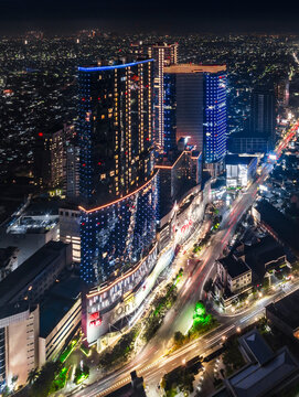 Aerial view of illuminated modern skyscrapers and light trails from traffic on the streets at night in Surabaya, East Java, Indonesia.