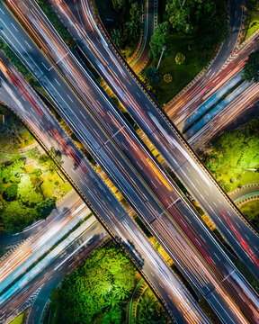 Aerial view of the Semanggi Interchange at night with long exposure light trails from traffic flowing through the highway junction surrounded by urban greenery Jakarta, Jakarta, Indonesia.