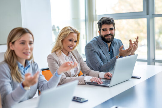 Smiling business people sitting at conference table during active discussion in meeting room
