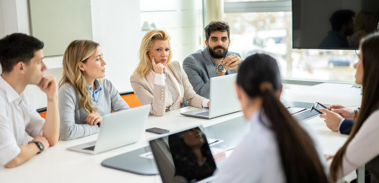 Focused corporate team listening to presentation around conference table in office