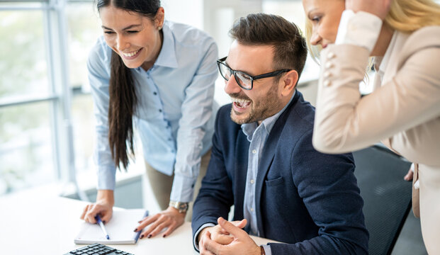 Happy business team laughing together while working on computer in office