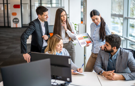 Corporate team analyzing printed business charts during informal meeting at workplace