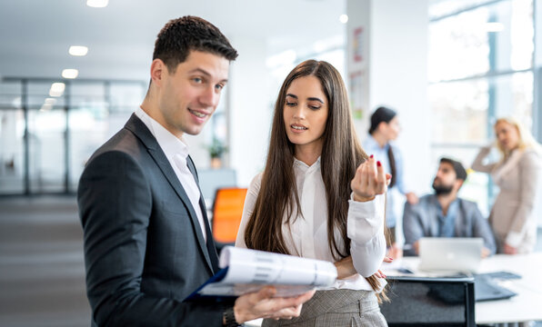 Businessman and businesswoman reviewing documents on clipboard together in hallway