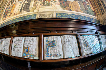 Obraz premium Antique choir books displayed in wooden cabinets in the famous Piccolomini Library, inside the Siena Cathedral (Duomo di Siena) in Tuscany, Italy. Built in the late 15th century (starting in 1492).