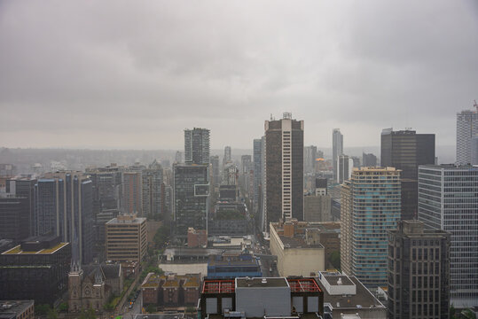 Aerial view of the dense Vancouver skyline featuring numerous high-rise buildings and skyscrapers under a cloudy, overcast sky in Vancouver, British Columbia, Canada.