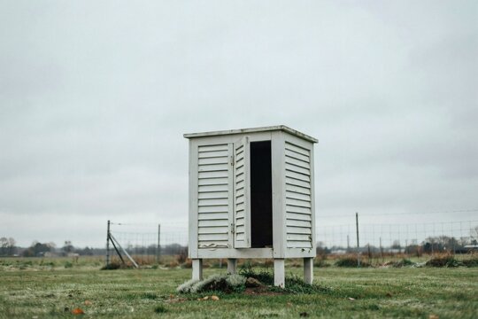Small Stevenson weather screen with its door ajar in a grassy monitoring enclosure