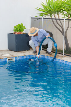Pool maintenance worker using cleaning machine at swimming pool
