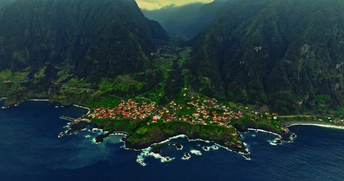 Aerial view of a small, picturesque village situated on an ancient volcanic formation that extends into the ocean and is washed by the waves of the Atlantic, on the island of Madeira, Portugal