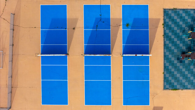 View Park-Windsor Hills, California, United States - 16 September 2026: Aerial view of 54th Street Elementary School with three blue pickleball courts on a cracked tan surface.
