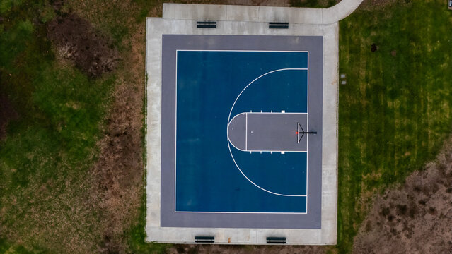 Los Angeles, California, United States - 16 September 2026: Aerial view of the basketball court at Kenneth Hahn Lower Park, with blue and grey markings surrounded by grass and benches.