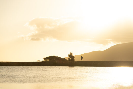 lone silhouette hiker at sunset walking nature path near water and mountains, Stanford, South Africa