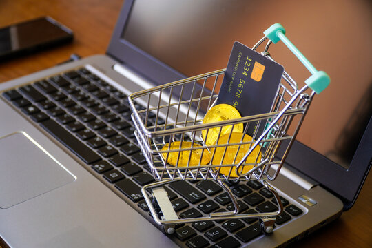 Miniature Shopping Cart with Bitcoins and Credit Card on a Laptop Keyboard