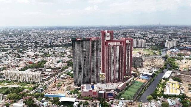 Drone shot showcasing the SPR City high-rise development in Perambur, Chennai, featuring distinctive red-and-white apartment towers, landscaped areas, construction activity, and a vast densely built