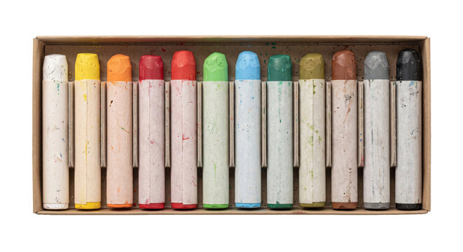 Full set of colorful used oil pastels in a cardboard box, viewed from directly above on a white background