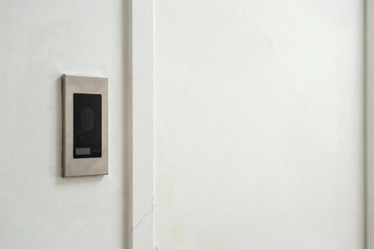 Wall mounted fingerprint access reader with a dark sensor pad in a corridor