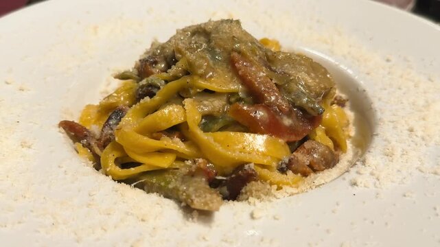 Homemade pasta with artichokes, cheese and pork cheek in Rome restaurant, traditional Italian dish, close-up food footage. High quality 4k footage