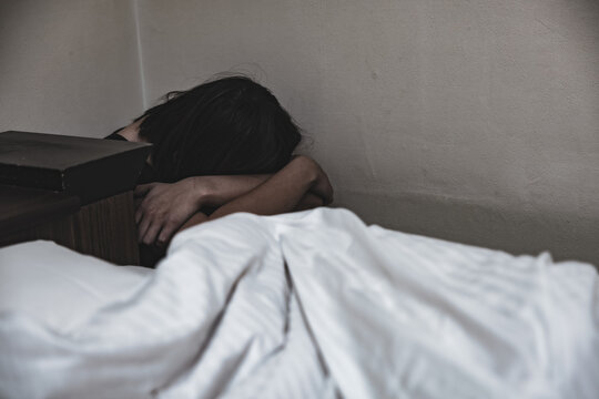 部屋の隅でうずくまり頭を抱える女性／メンタルヘルス・うつ・心理的ストレスのイメージ