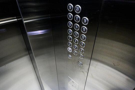 Stainless steel elevator panel with circular floor buttons, numbers 1&ndash;20, metallic finish, subtle reflections, clean industrial design, vertical layout, minimal wear