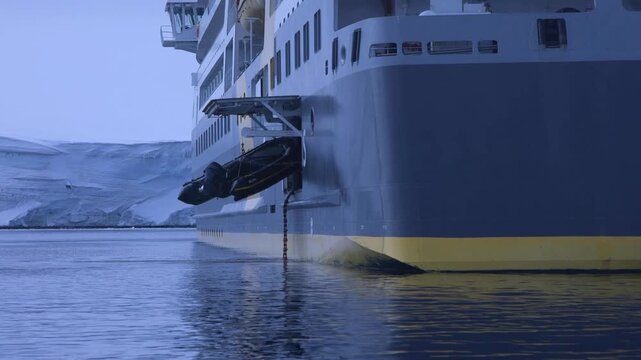 A Zodiac being Winched out of the Blue Sea and into the Hull of a Large Ship in the Antarctic Peninsula