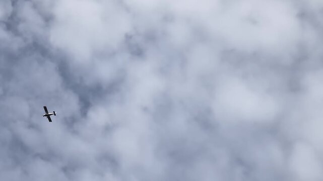 Light sports plane flies in the sky with engine sound above a cloudy landscape