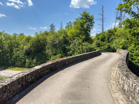 Stone parapets along a curving woodland lane
