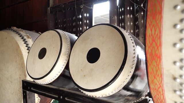 Row of traditional Thai drums showing plain leather heads and metal rivets in a factory.