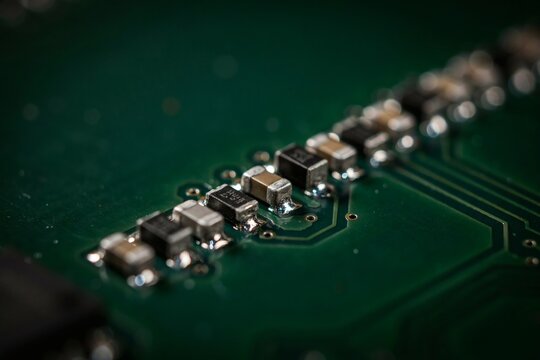 Macro of surface-mount capacitors and solder joints along a dark green board