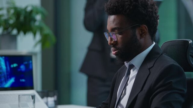 Two multiethnic business men talking phones in office. Businessmen talk mobile calls. African American agent answering smartphone typing computer Caucasian male with digital tablet speaking cellphone
