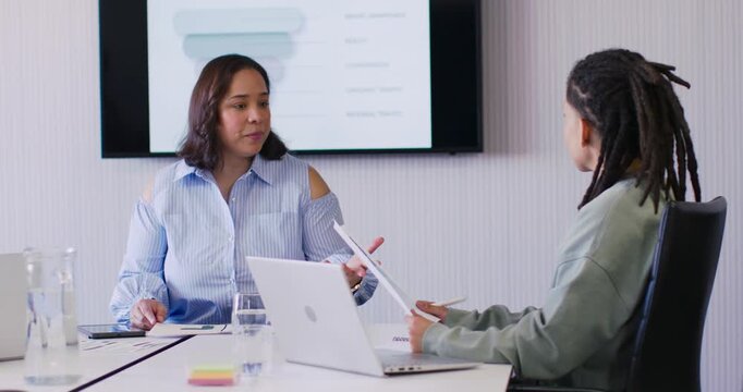 Two office colleagues using color swatch, starting design review, exchanging pages and using laptop