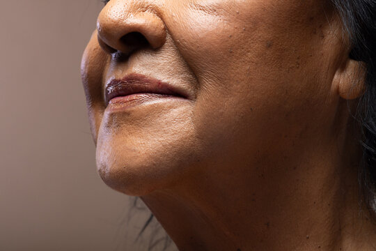 Senior African woman showing lower face and neck in studio, highlighting dark lipstick