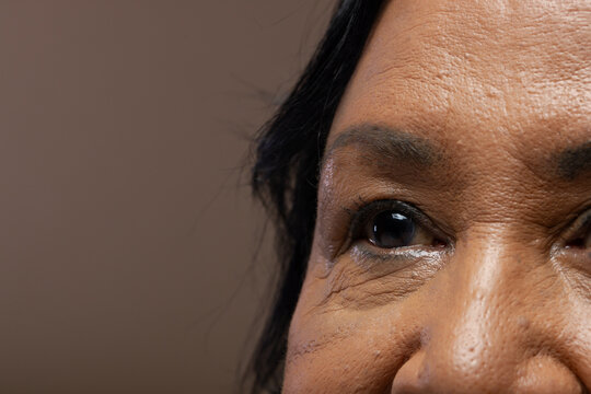 African American senior female showing textured skin and fine lines, focusing on eye in studio