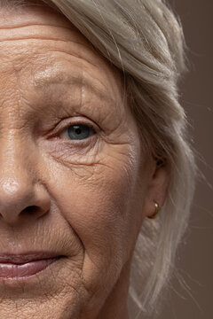 Senior woman posing closeup under soft angled studio light, showing textured skin