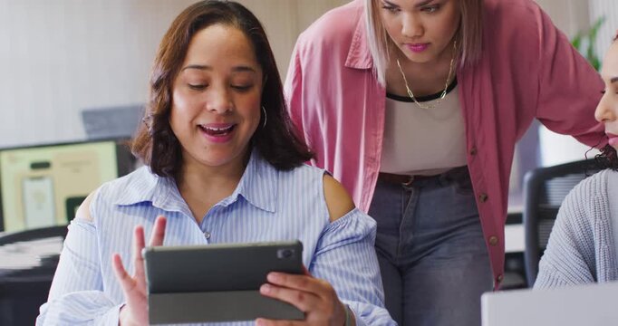 African American female team watching seated woman showing tablet in folio case, tapping for review