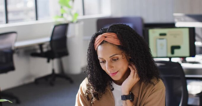 African American woman in light brown jacket sitting at desk in modern office, reacting to laptop