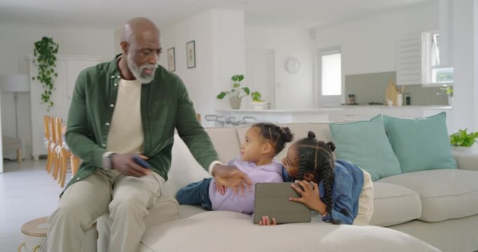 African American family watching man reaching for folio for two youth girls to inspect on ottoman