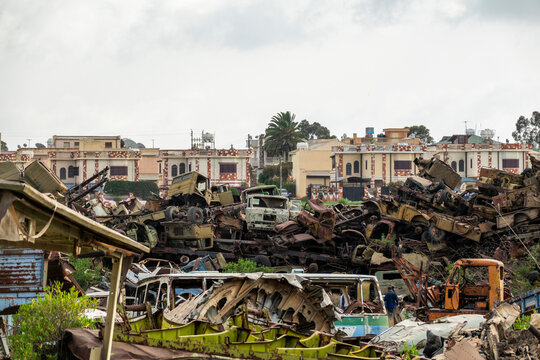 Luxury villas built for war heroes rise behind piles of rusted military truck wreckage at the tank graveyard, Central Region, Asmara, Eritrea