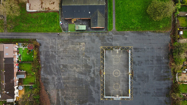 Open basketball court beside a vacant lot in a suburban neighborhood during the day