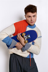 Young stylish man showcasing fashion while holding a skateboard © LIGHTFIELD STUDIOS