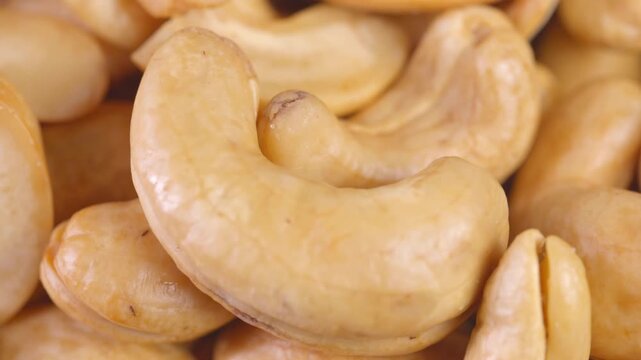 Macro close-up shot showcasing the natural texture and golden tone of fried cashew kernels against Perfect for food, nutrition, and healthy	