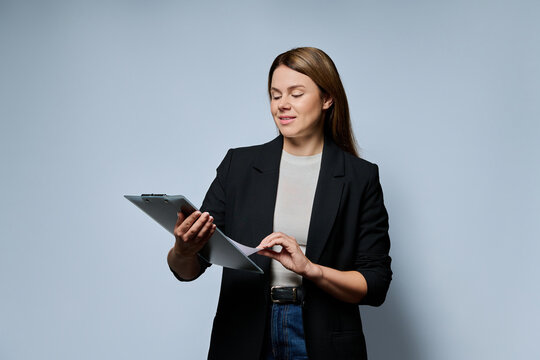 Female teacher looking at documents on clipboard studio portrait