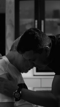 Adult son embracing aging father struggling with dementia indoors providing compassionate support comfort and emotional relief