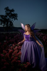 Beautiful young girl in a purple fairy costume with wings holding a magic wand © Nataliya