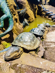 Large tortoise sculpture beside a pond in a themed park in Vietnam. Smaller turtle figures line the path. Useful for travel guides, family attractions, tourism blogs and park features. © Kate