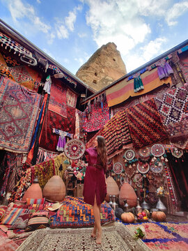 a beautiful girl in dress in a traditional turkish interior with many carpets on the wall