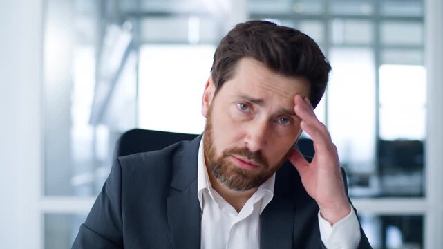 Portrait unwell unhappy Caucasian middle-aged business man holding head looking at camera feeling head painful migraine in office tired exhausted mature businessman male executive with headache indoor