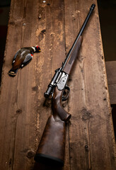 Obraz premium Hunting and wildlife conservation, rifle with scope and harvested game bird on rustic wooden table for outdoor sport and traditional field recreation