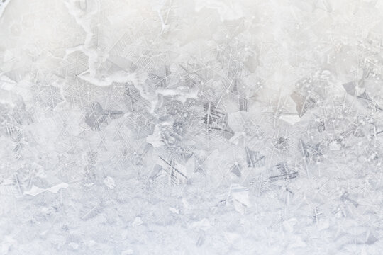 white winter background, frosty patterns on glass, abstract backdrop of ice and snow crystals in a blur